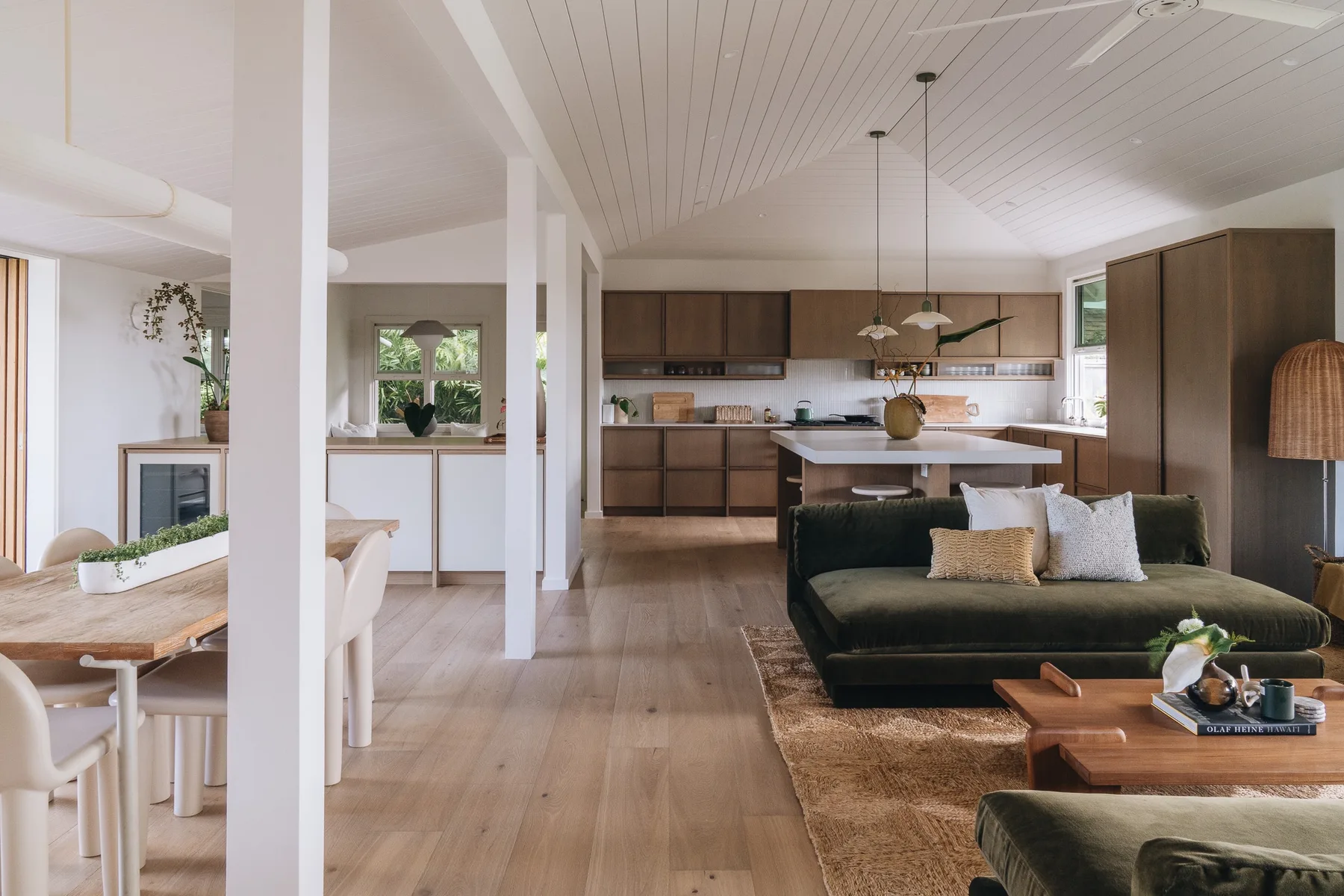 An open-plan living and dining area with a kitchen and dark seating.