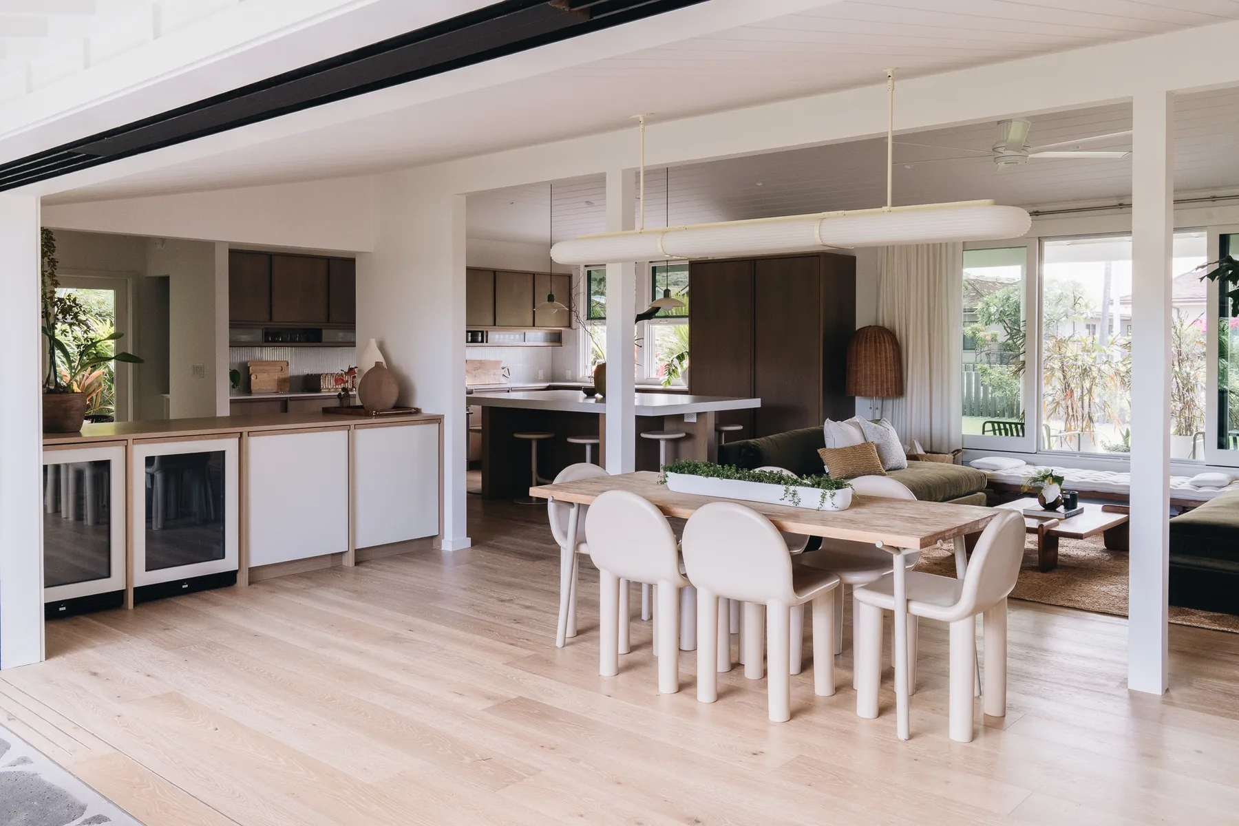 Open-plan dining and kitchen area with a long table and surrounding seating.