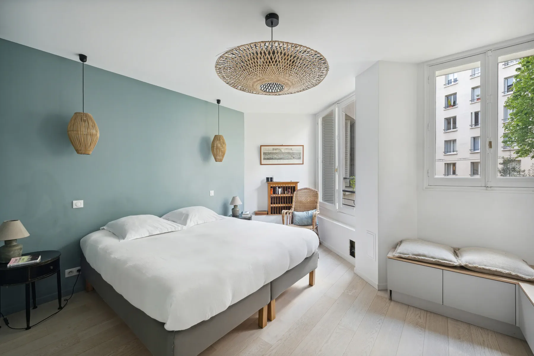 A bright bedroom with a large bed beside tall windows.