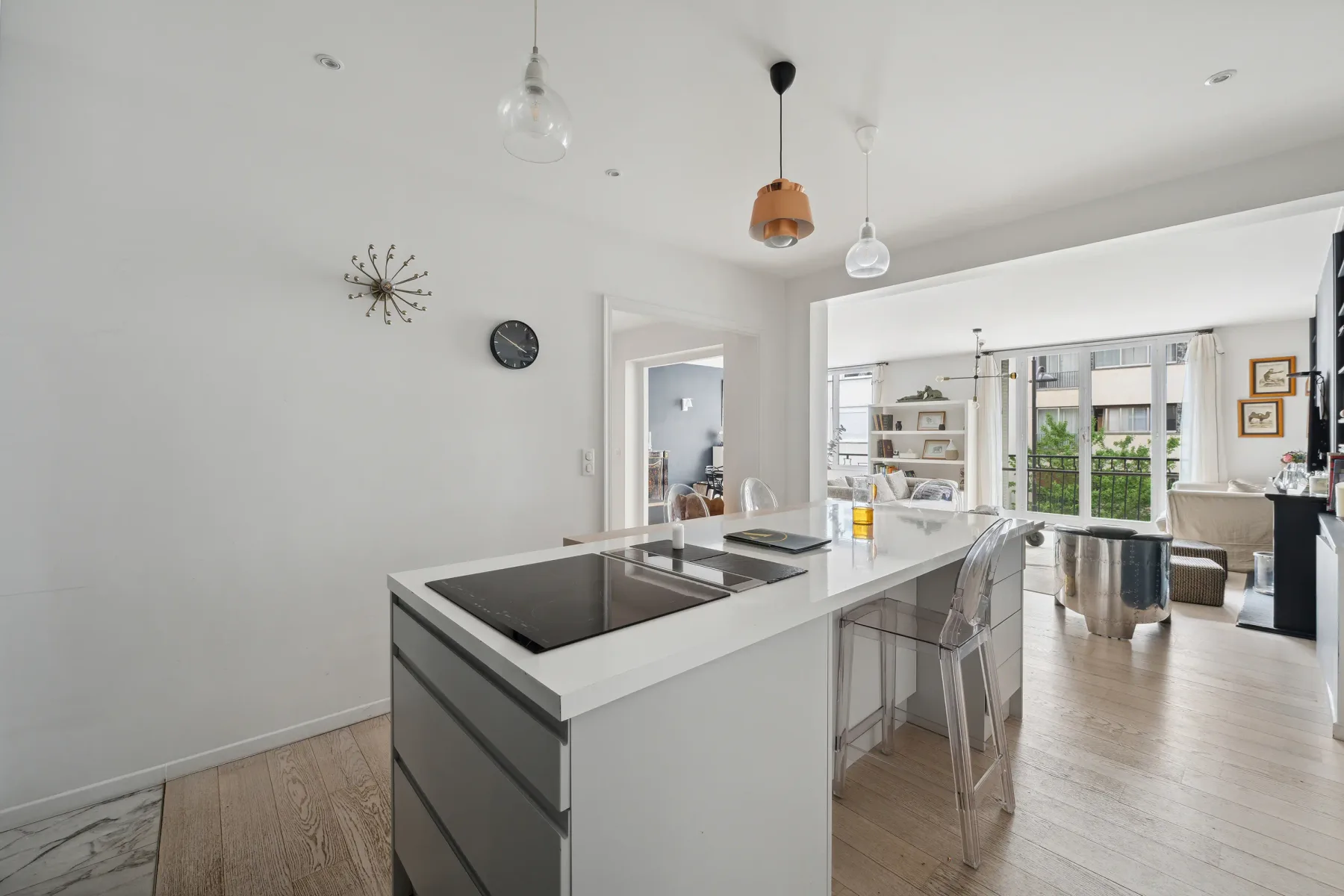 A bright open-plan kitchen and dining area with a central island and large windows.