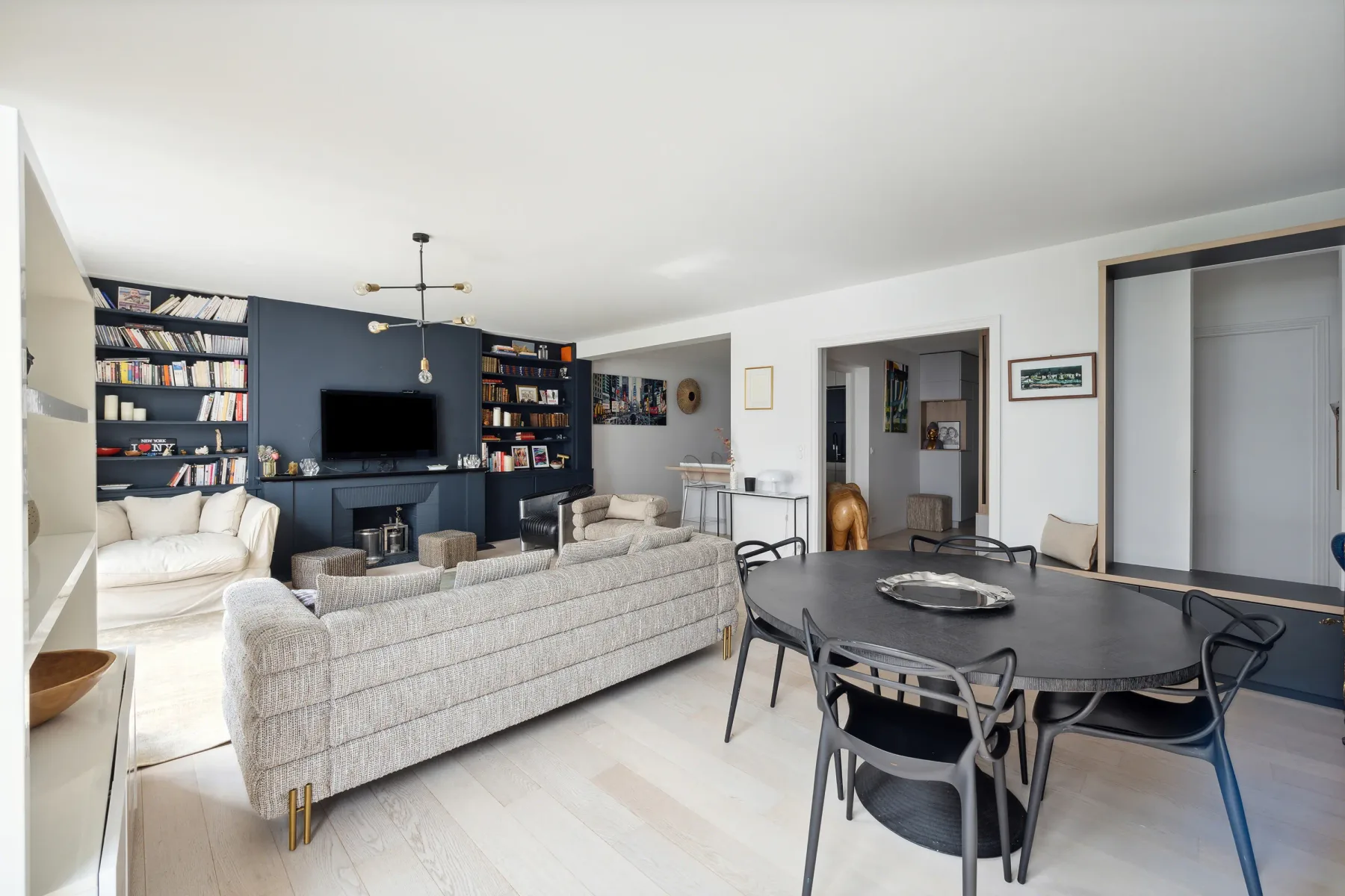 A bright open-plan living and dining area with dark built-in shelving.