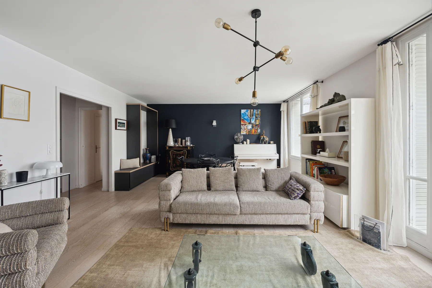 A bright living room with a sofa, glass coffee table, and large windows.