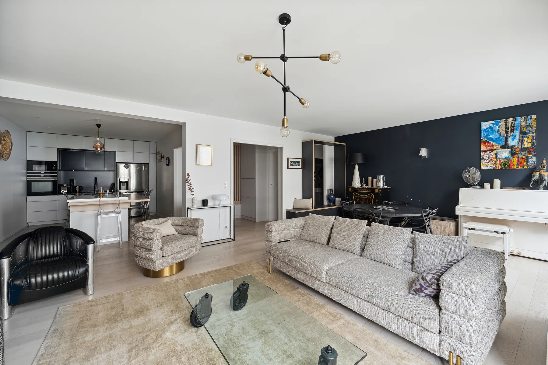 A modern living room with a gray sectional sofa and an open kitchen.