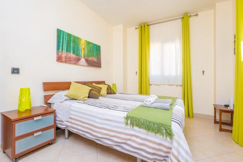 Un dormitorio con una cama a rayas y cortinas verde brillante.