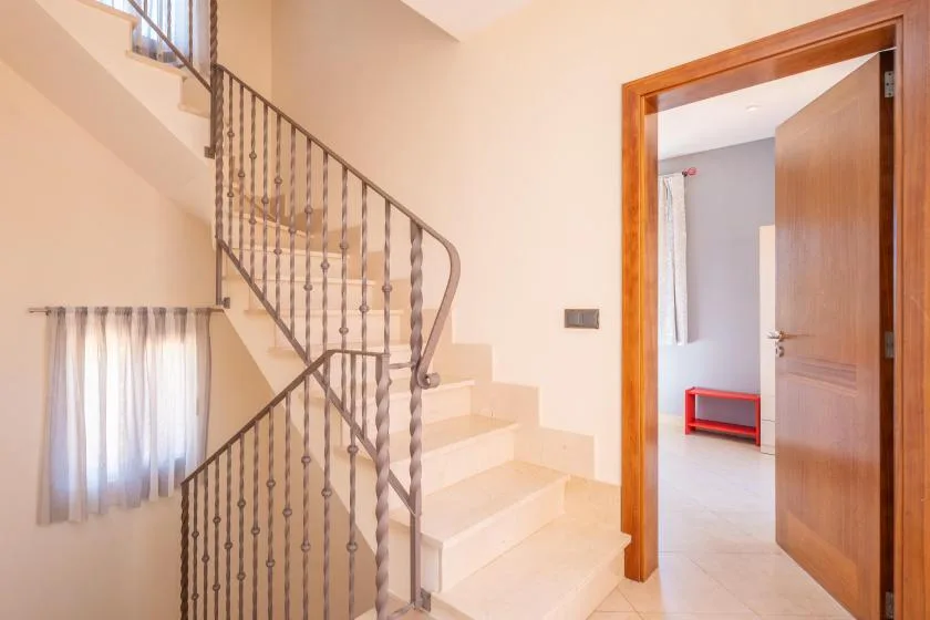 Una escalera con barandales metálicos oscuros conduce a una puerta abierta.
