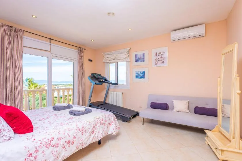 Un dormitorio con una cama, una cinta de correr y asientos junto a la pared.