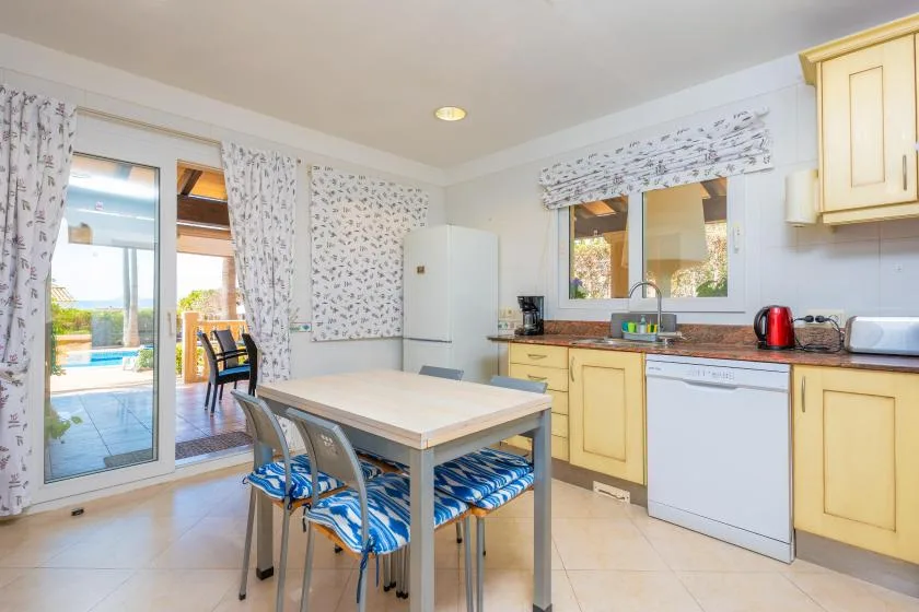 Una cocina luminosa con comedor y una mesa junto a puertas de vidrio que dan a un patio.