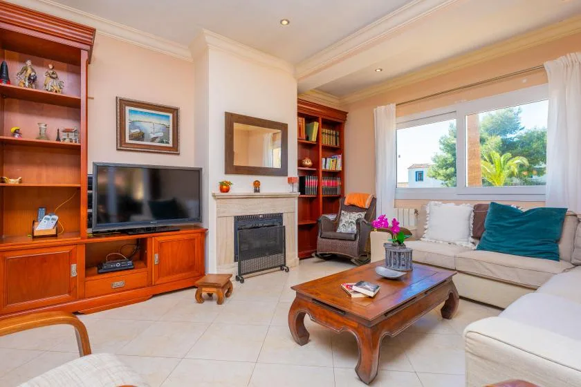 Una sala de estar con televisor, chimenea, asientos y una mesa de centro de madera.