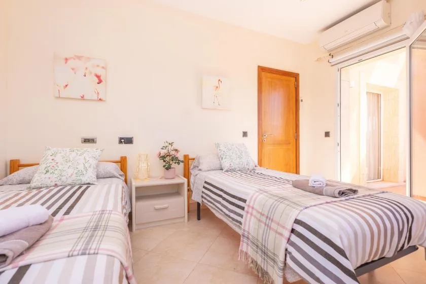 Un dormitorio con dos camas, ropa de cama a rayas y una puerta de madera.