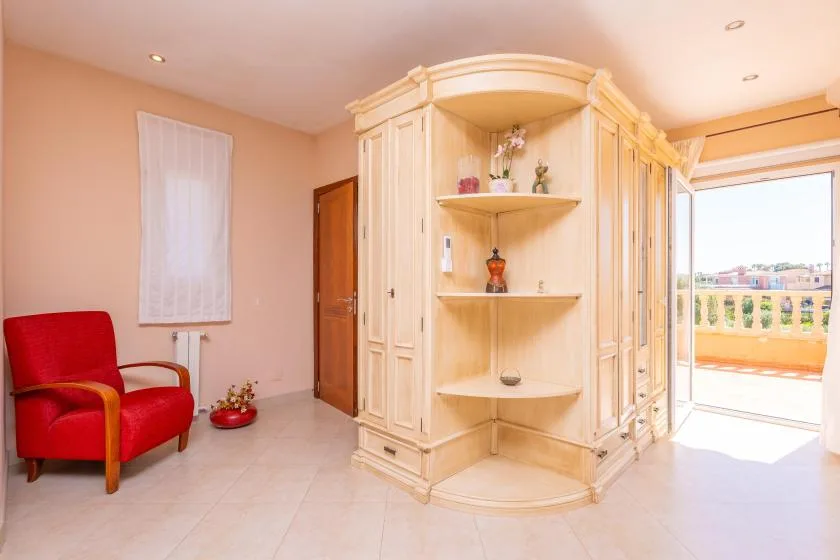 Una habitación luminosa tiene un gran armario empotrado y un sillón rojo.