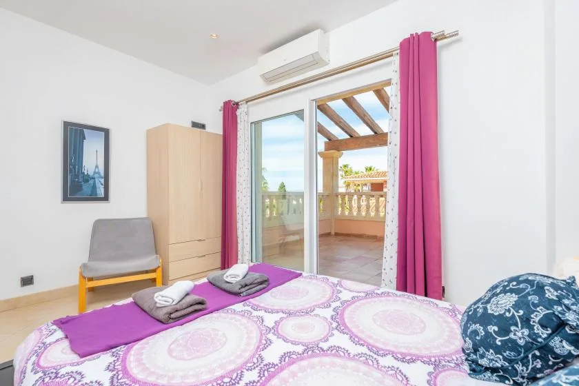 Un dormitorio con una colcha estampada y puertas corredizas de vidrio que dan a un balcón.