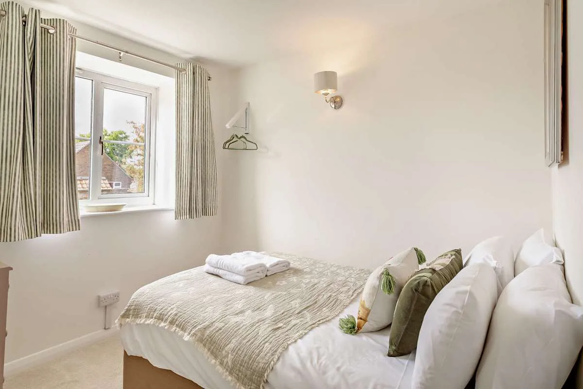 A bedroom with a neatly made bed and a window with curtains.