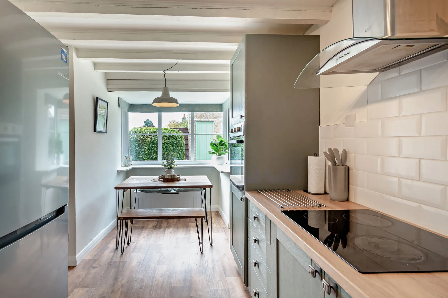 A bright kitchen opens onto a dining area beside a large window.
