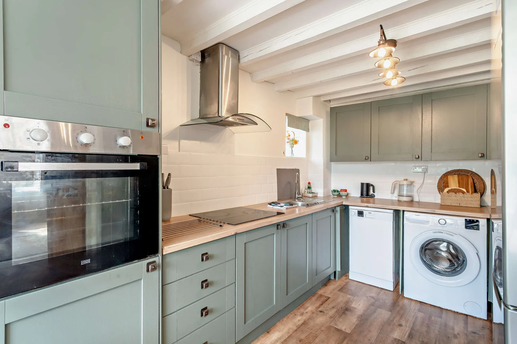 A kitchen with green cabinets, a built-in oven, and laundry appliances.