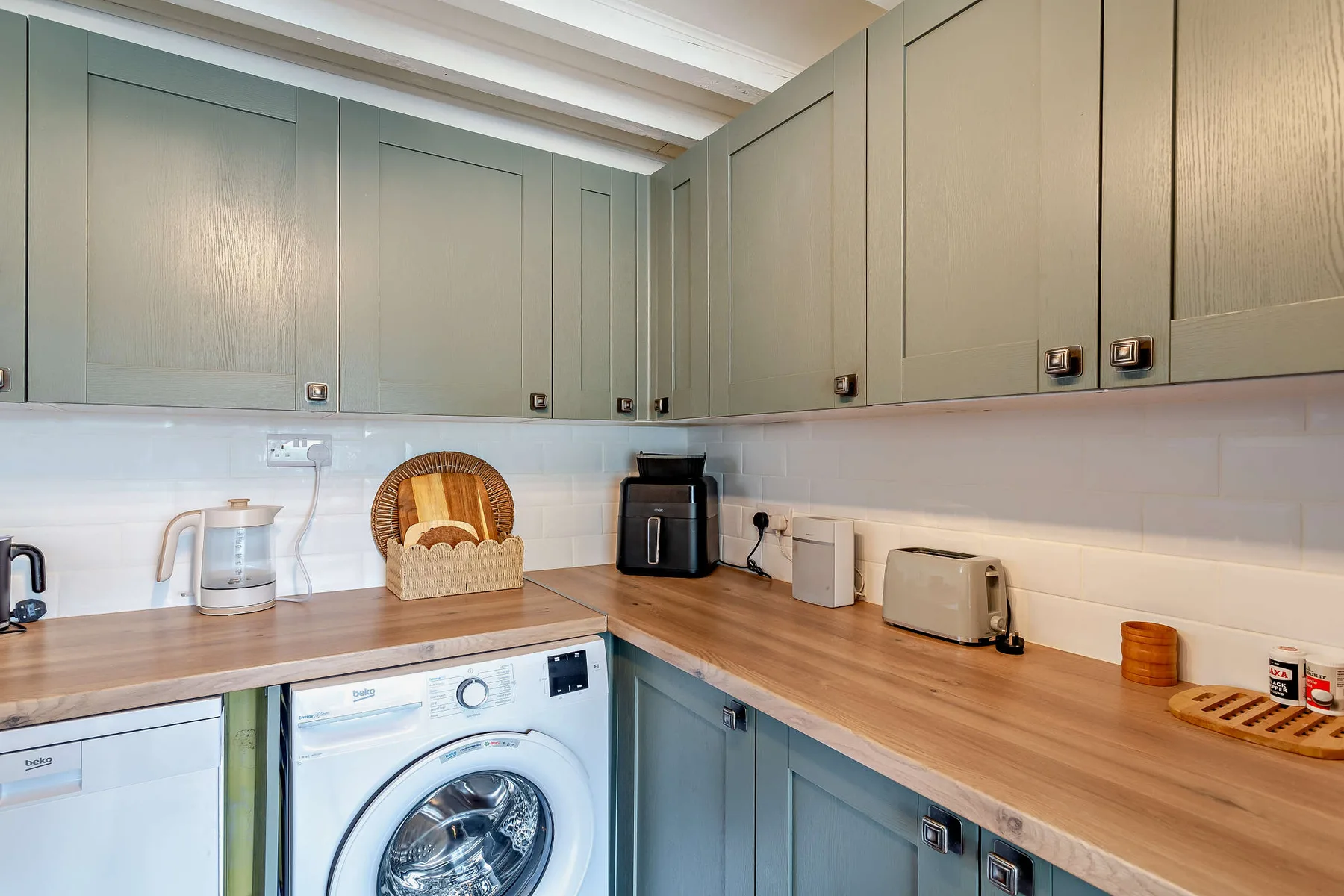 A laundry and utility room with a washing machine beneath a wood countertop.