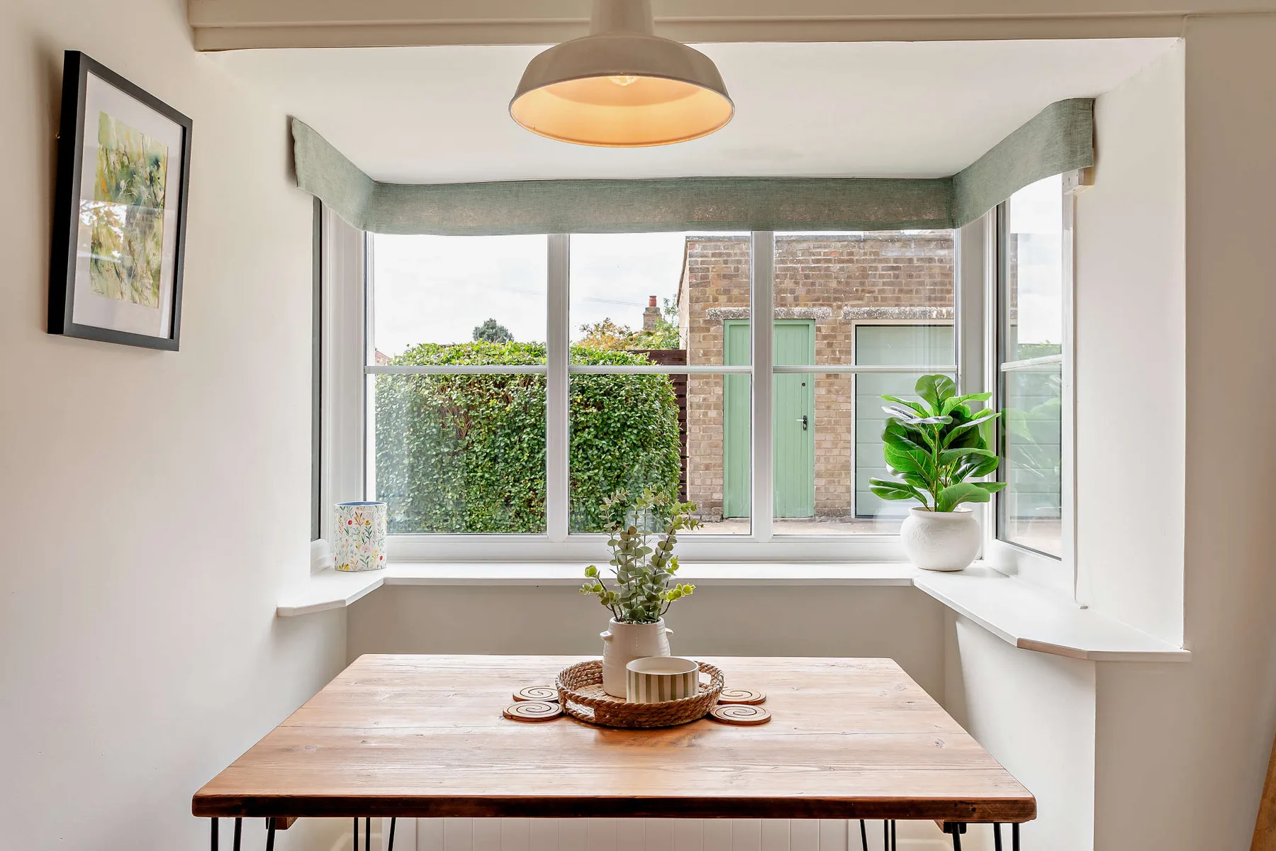 A bright dining nook with a wooden table beside large windows.