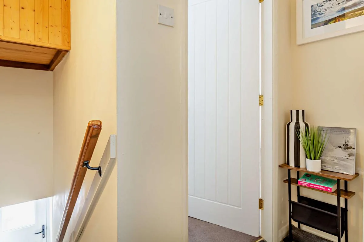 A cottage hallway with a staircase and a narrow display table.