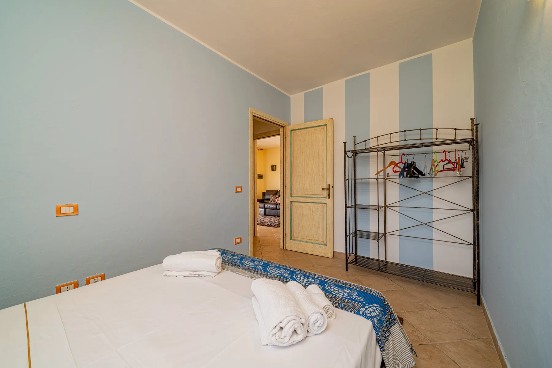 Un dormitorio con una cama, toallas dobladas y una puerta abierta.