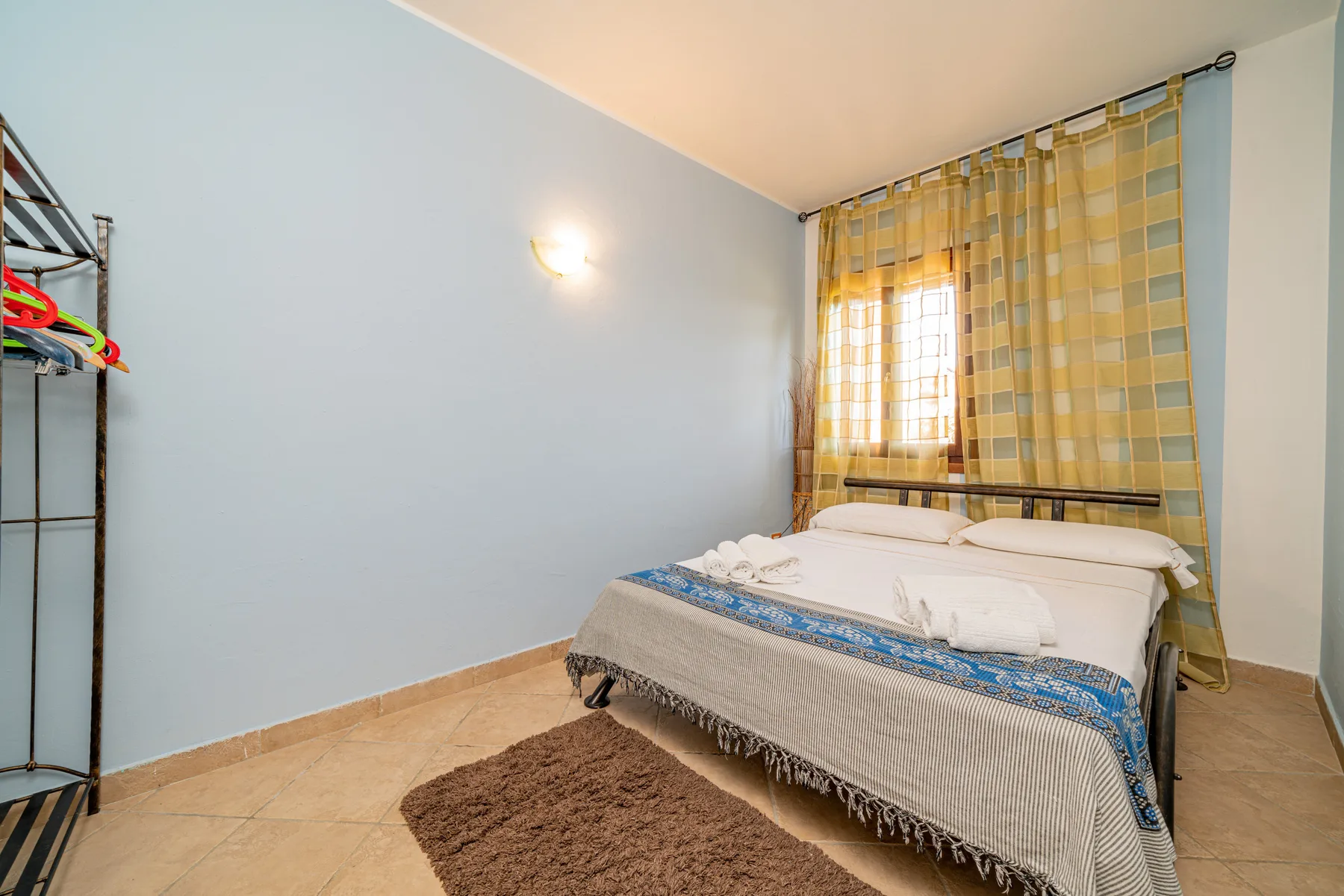 Un dormitorio con una cama bien arreglada y cortinas amarillas a cuadros.