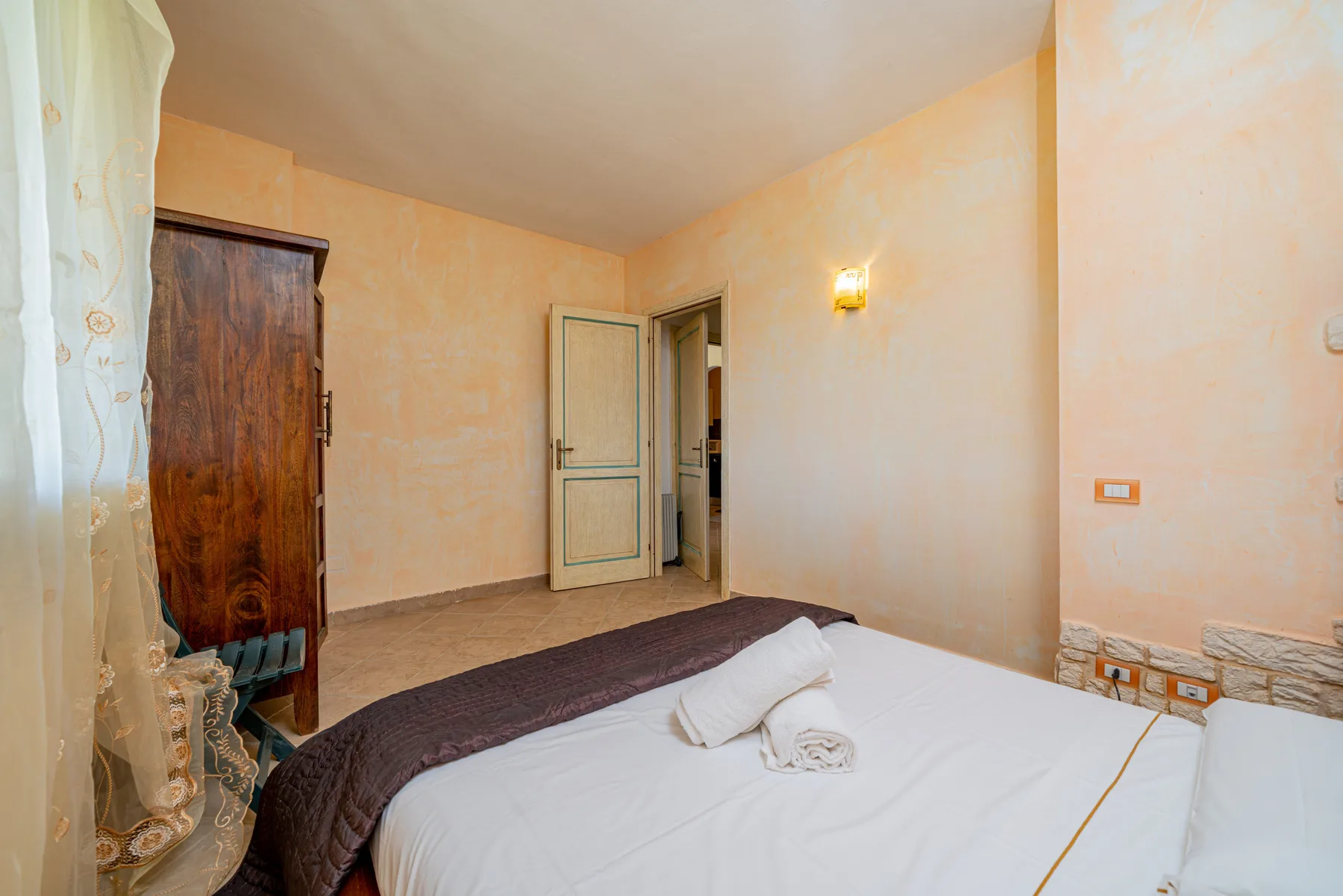 Un dormitorio con una cama bien tendida y una ventana con cortinas.