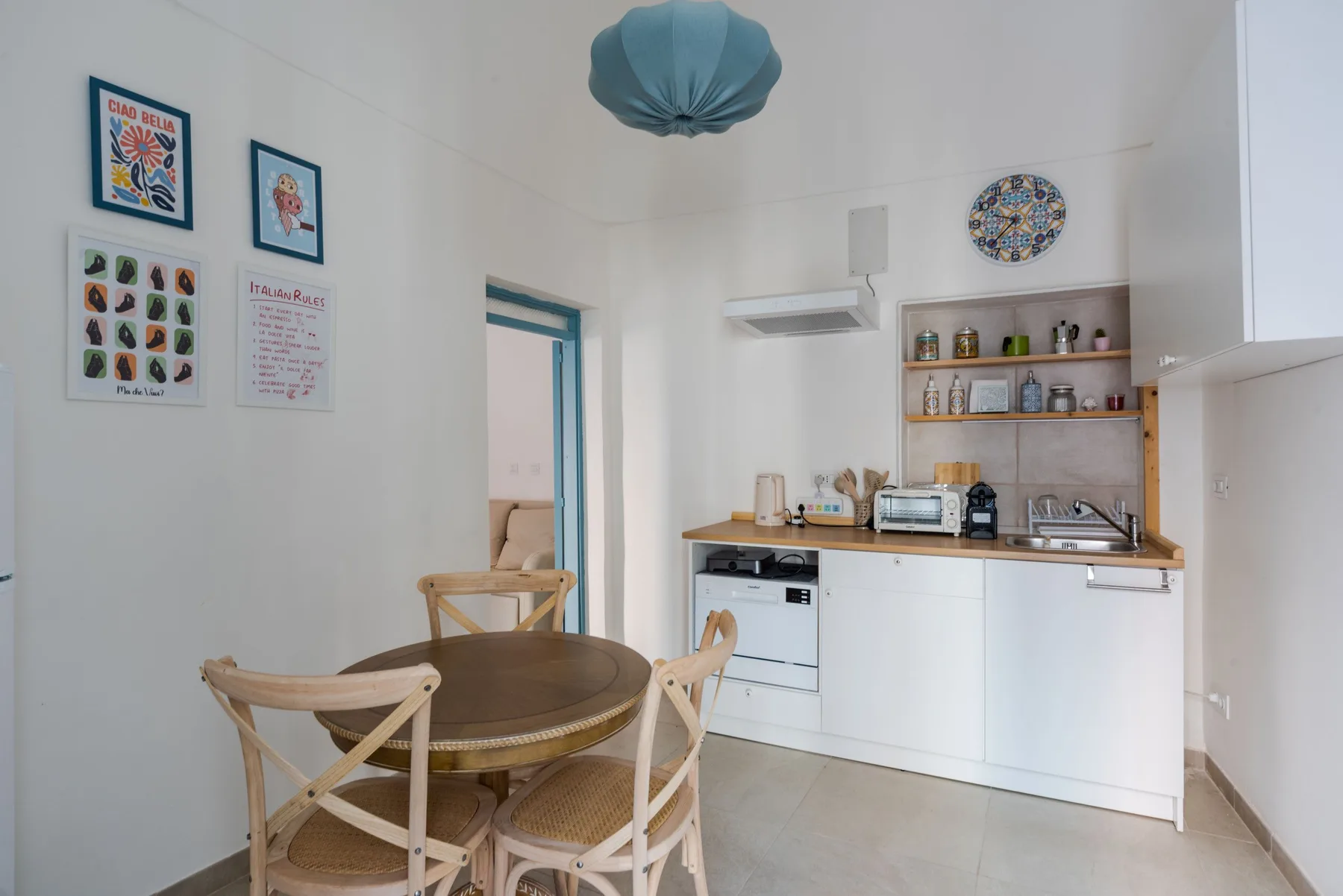 A bright kitchen and dining area with a round table and open shelving.