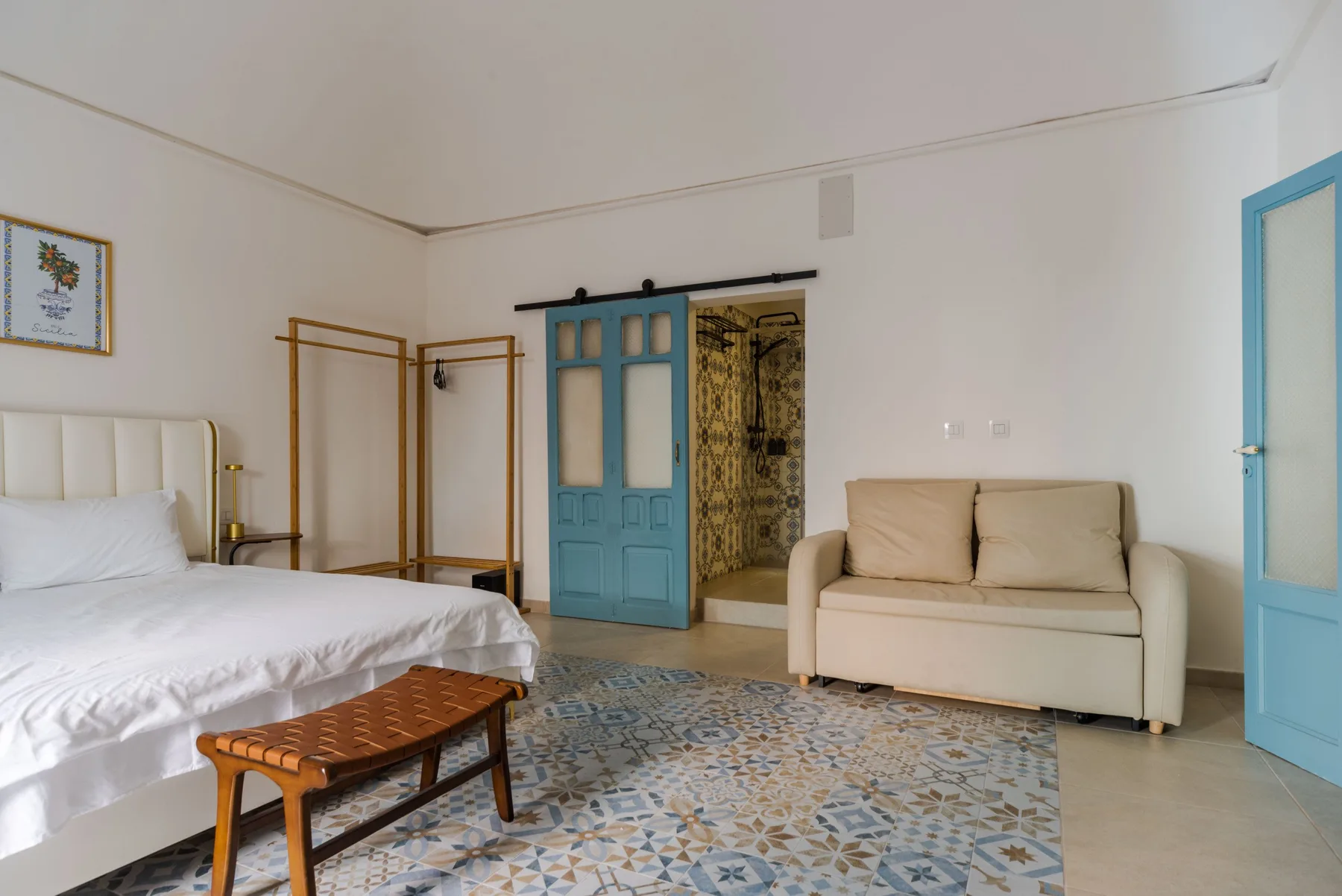 Un dormitorio con una cama, una mesa pequeña y asientos sobre un suelo estampado.