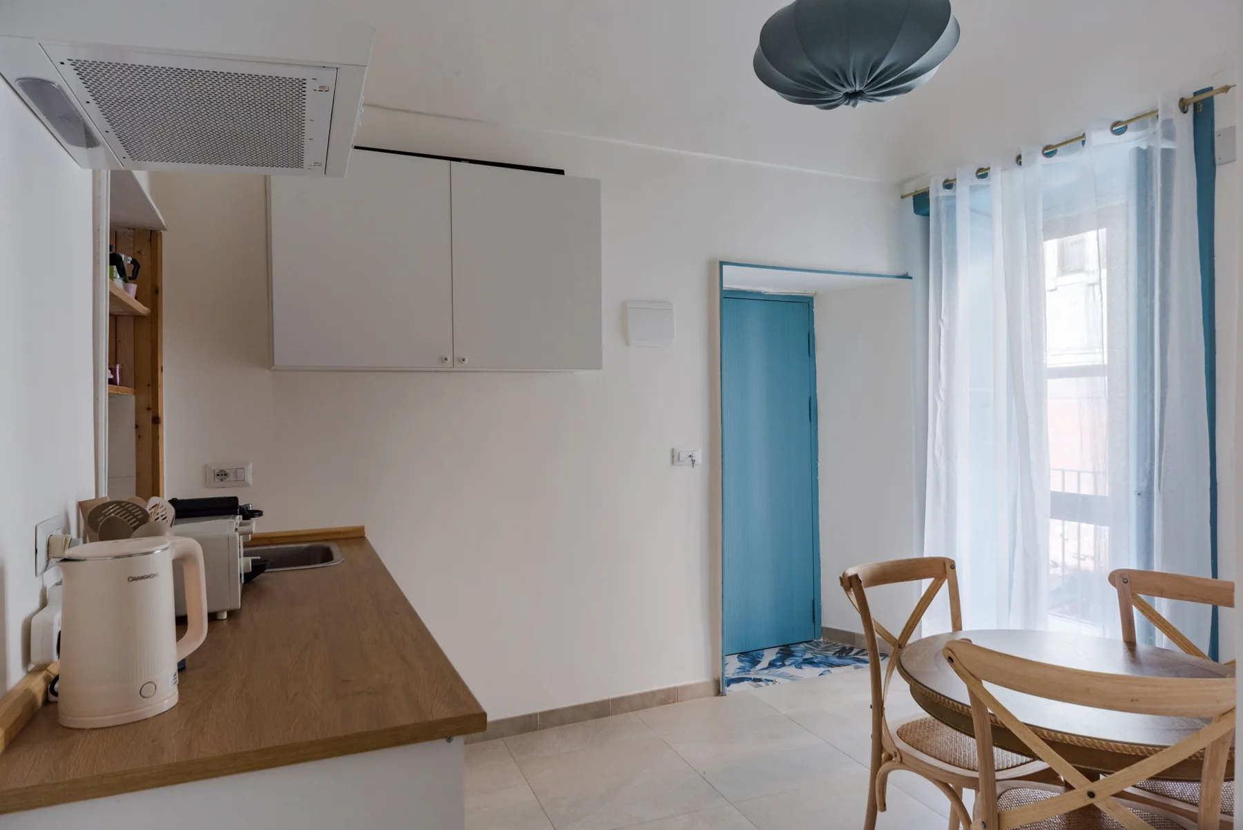 Una cocina luminosa con zona de comedor, encimera de madera, mesa y sillas.