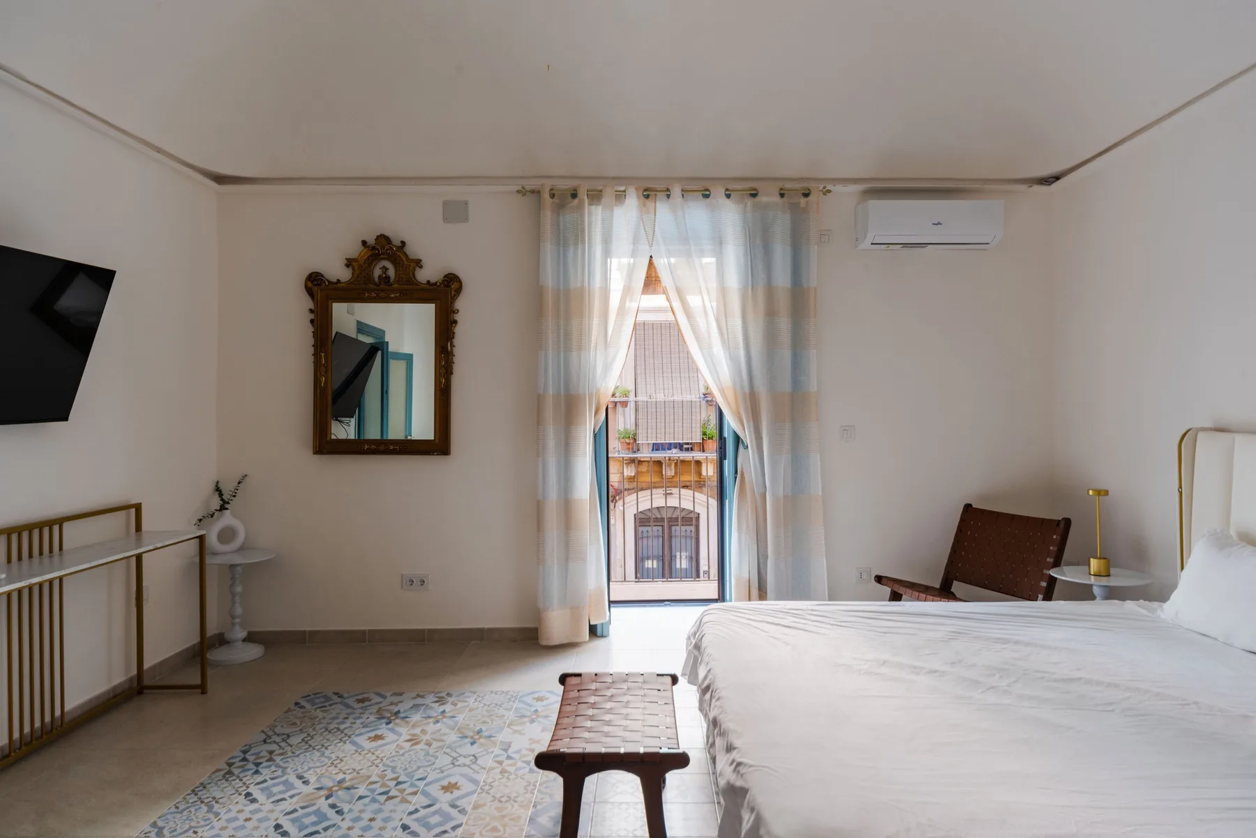 Un dormitorio con una cama, una ventana con cortinas y una mesa pequeña.