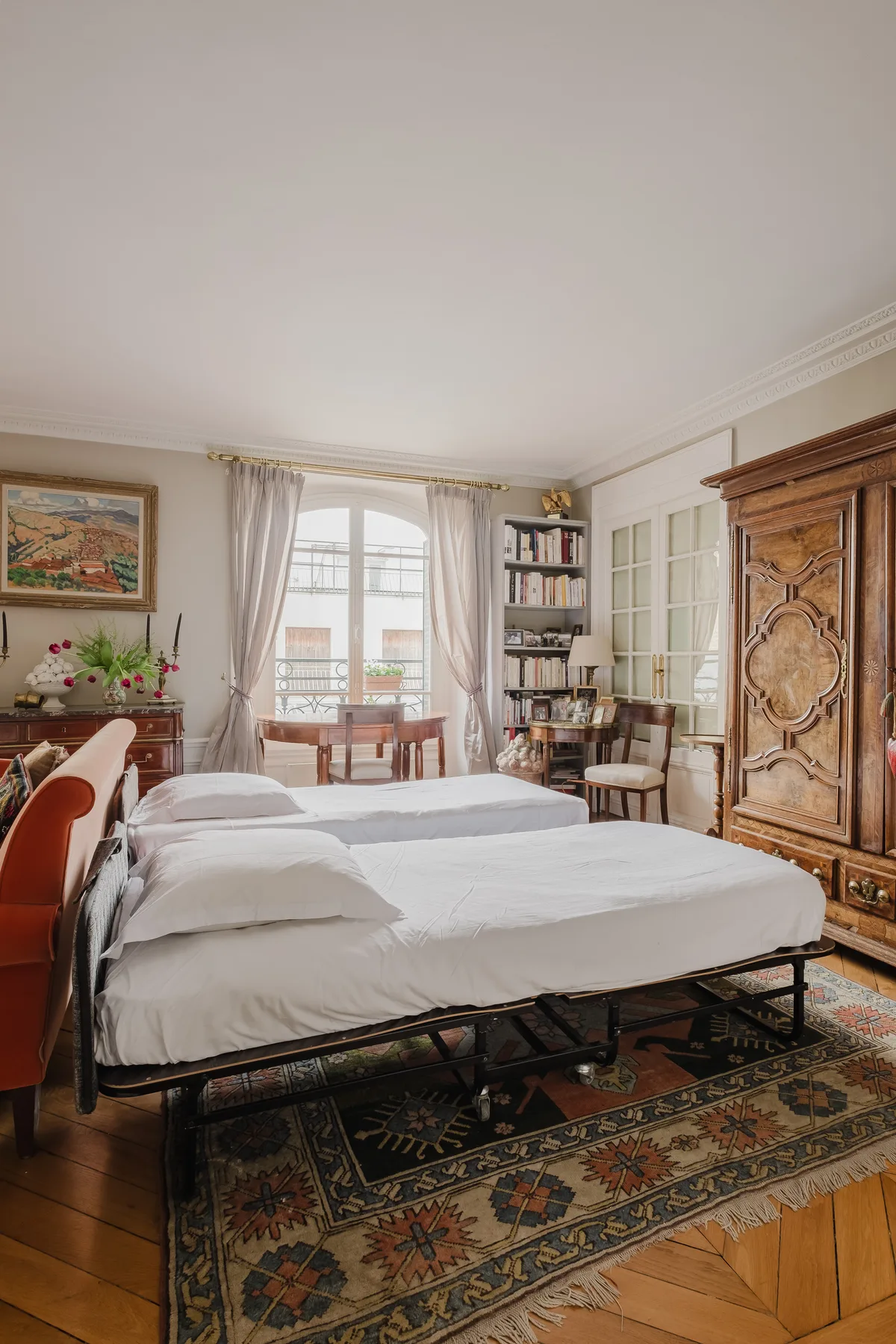 A bedroom with two beds, a window, and a patterned rug.