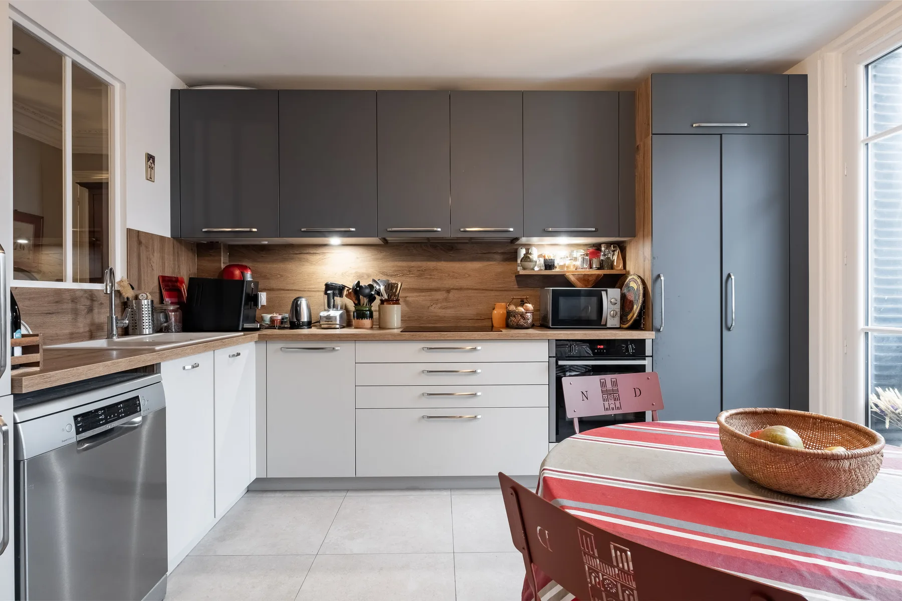 A modern kitchen with dark upper cabinets and a red-striped dining table.
