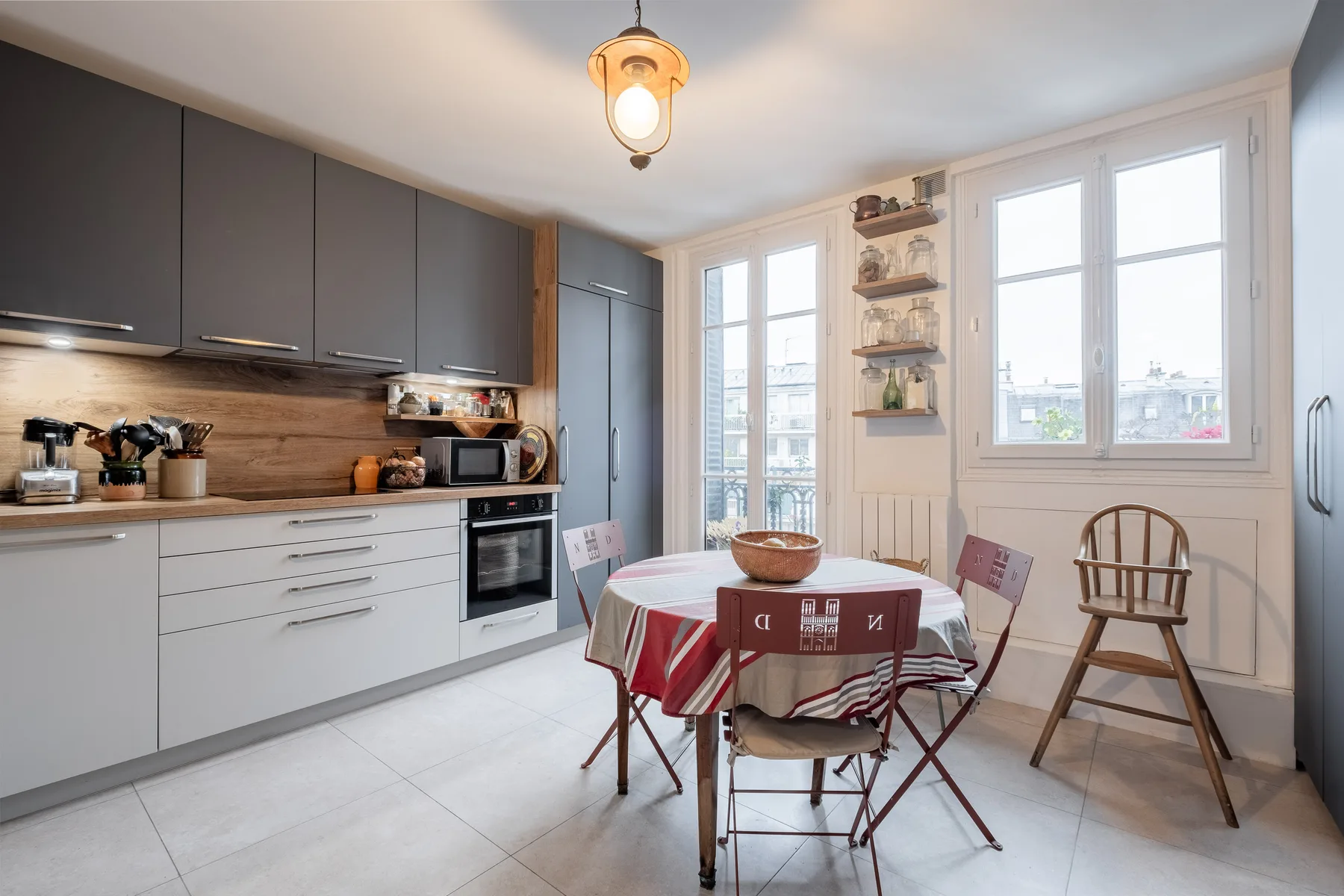 A kitchen dining area with a table beside large windows.