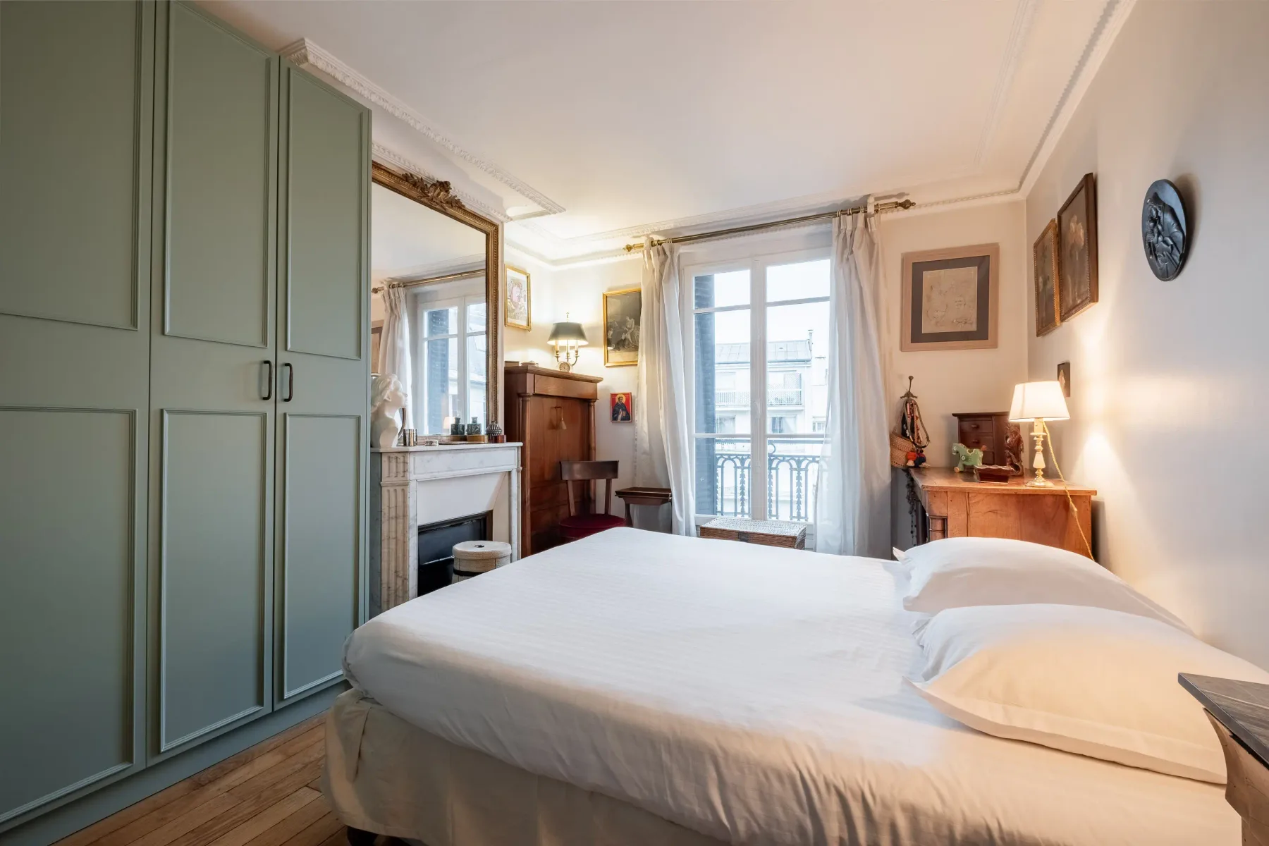 A bedroom with a large bed facing tall windows and a balcony door.