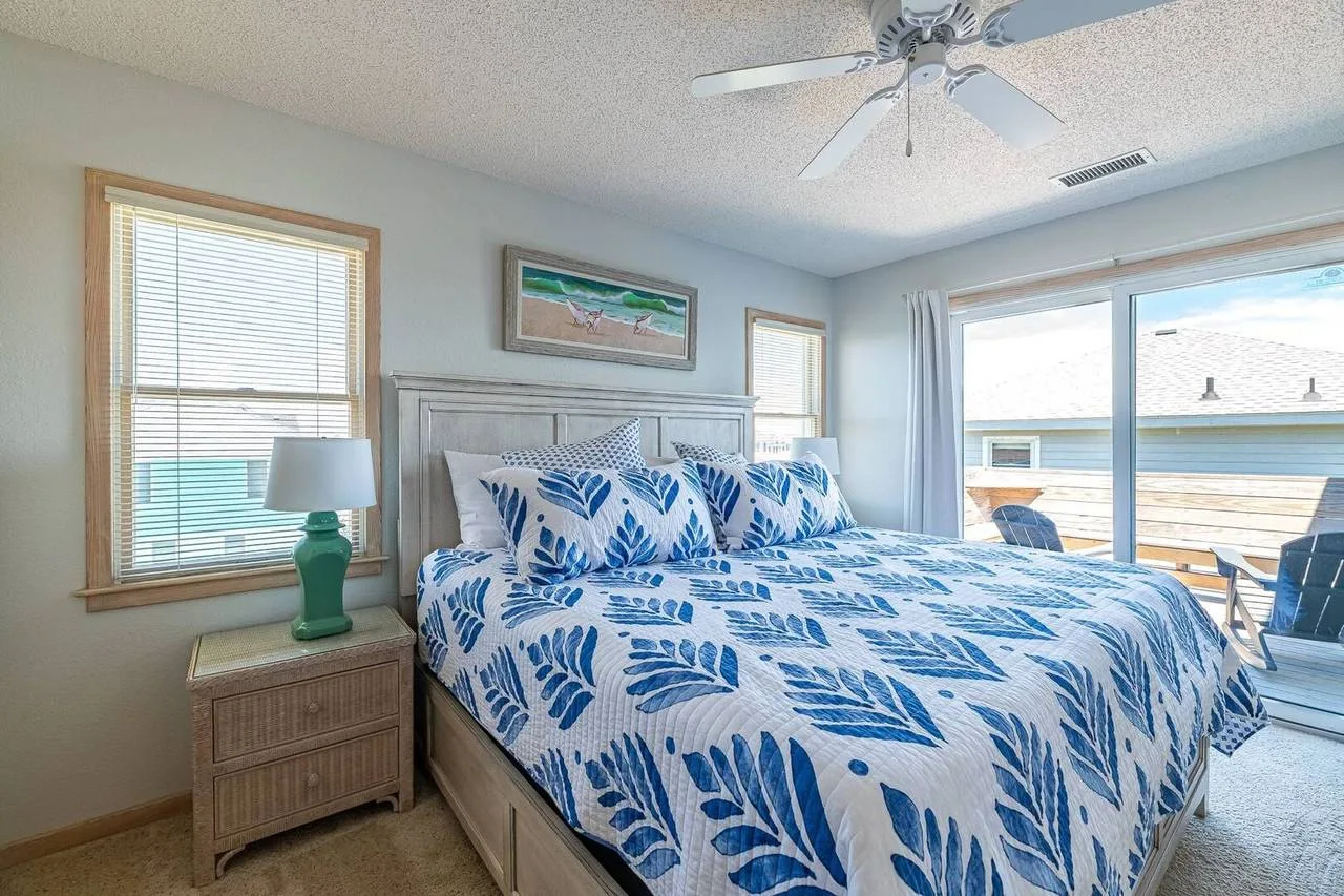 A bedroom with blue-and-white bedding beside a bright window.