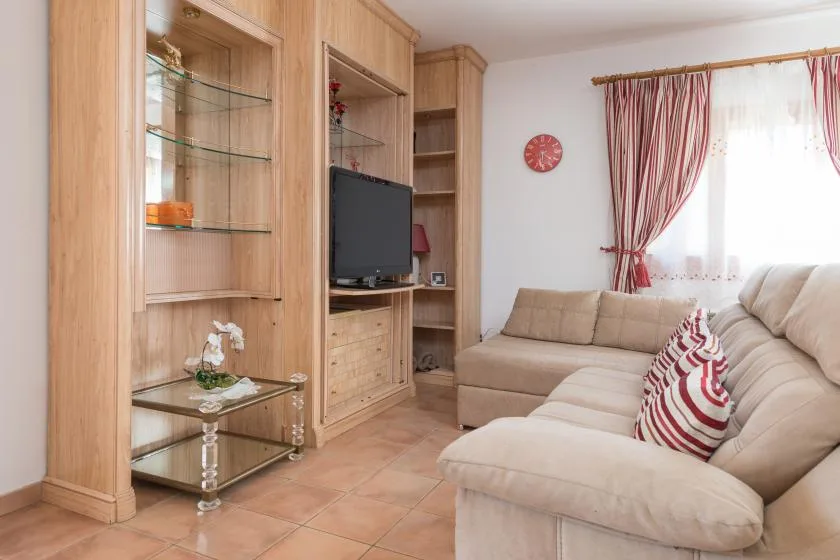 A living room with beige seating, built-in wooden cabinets, and a television.