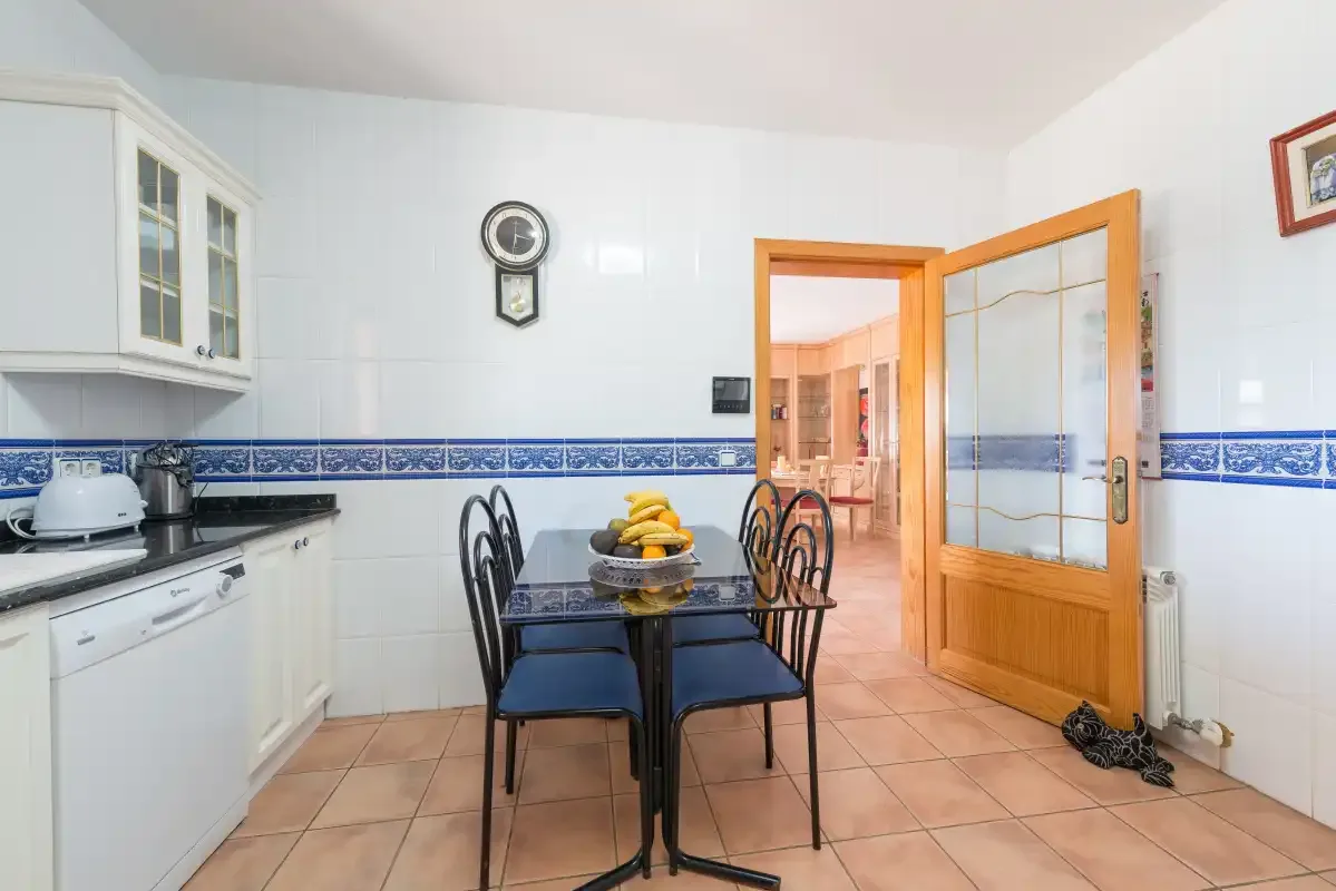 A tiled dining area with a table and chairs beside the kitchen.