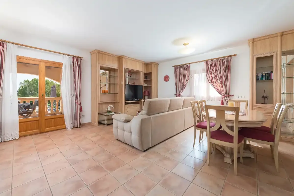 A living and dining area with a television, seating, and a wooden dining table.