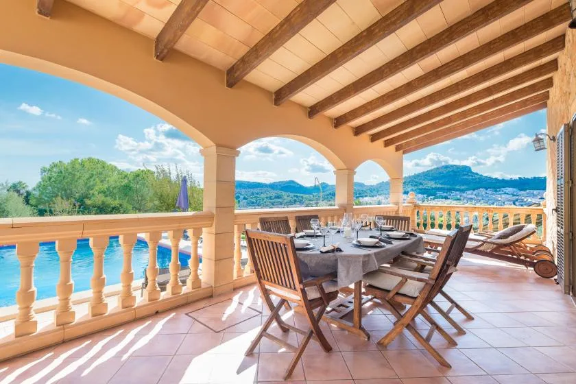 A covered outdoor dining area with a table and chairs overlooking the landscape.