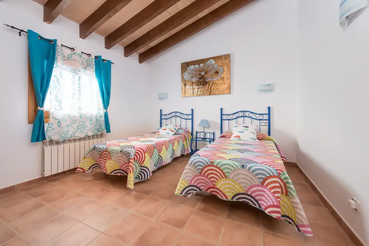 A bedroom with two single beds beneath exposed wooden ceiling beams.