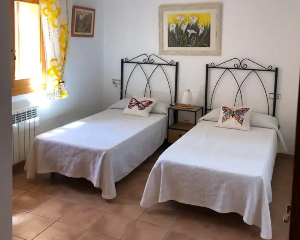 A bedroom with two single beds and a small table between them.