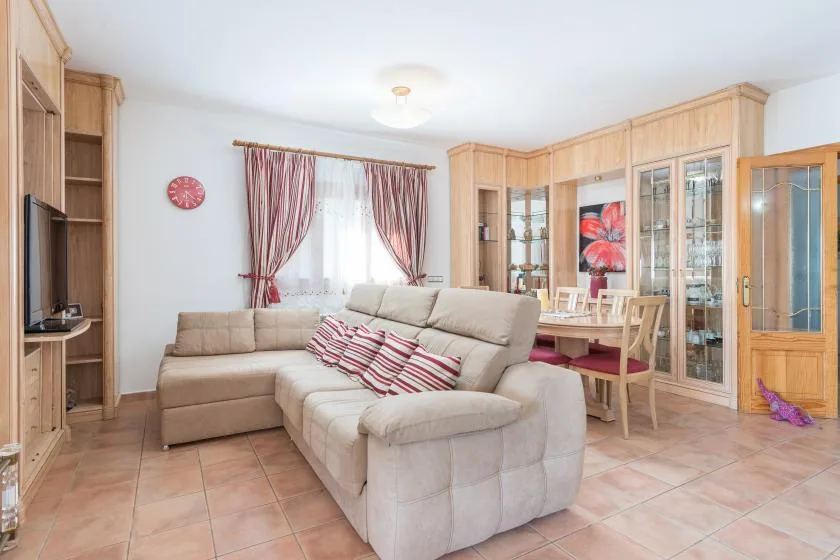 A living room with a sectional seating area and a dining table.