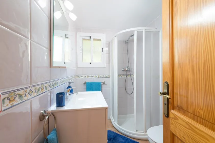 A bright bathroom with a sink vanity and a curved glass shower.