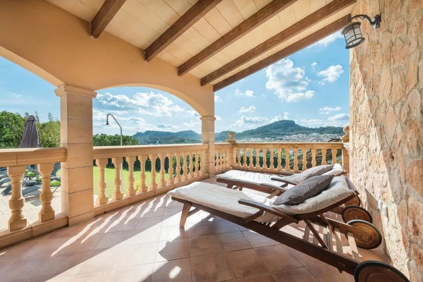 A covered terrace with reclining seating overlooks the water and distant hills.