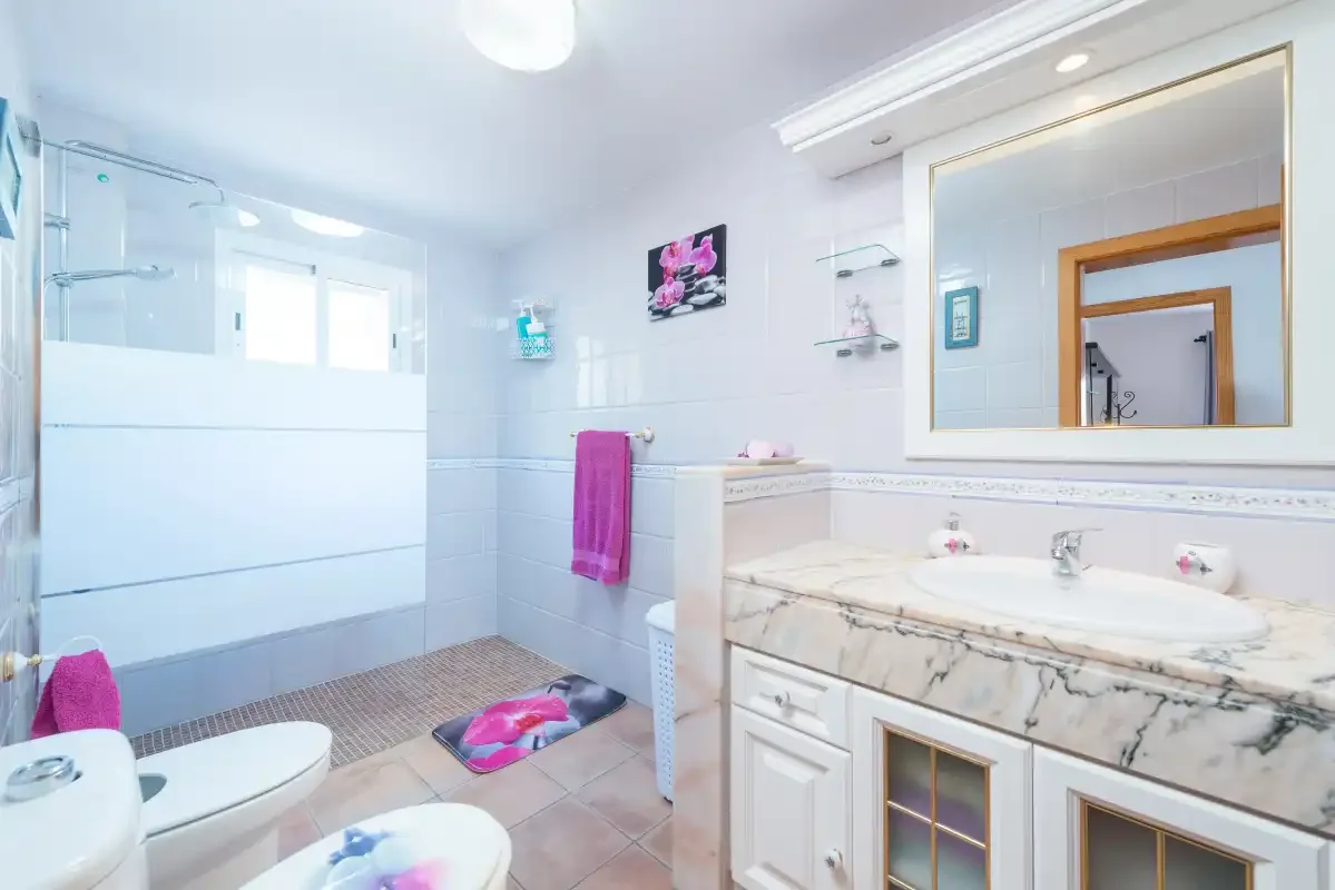 A bright bathroom with a glass shower, sink, and large mirror.