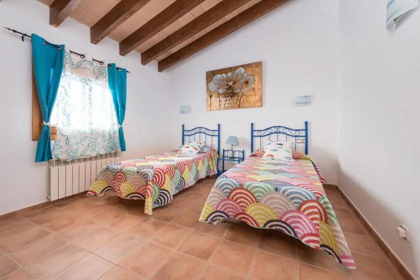 A bedroom with two single beds covered in colorful patterned bedspreads.