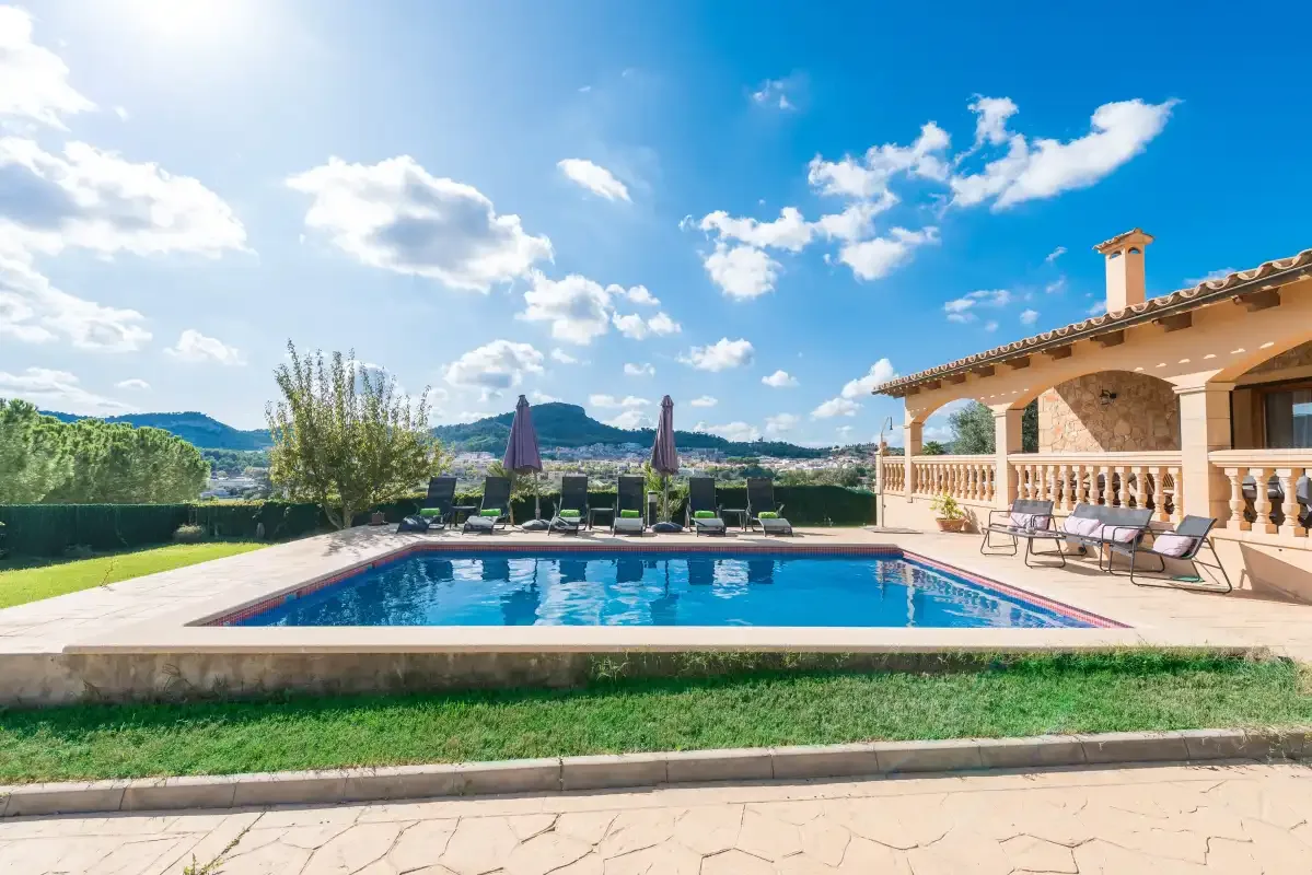 A swimming pool beside a paved patio and a covered seating area.