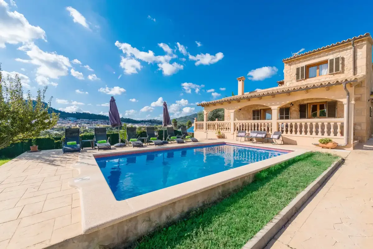 A villa overlooks a swimming pool and patio seating.