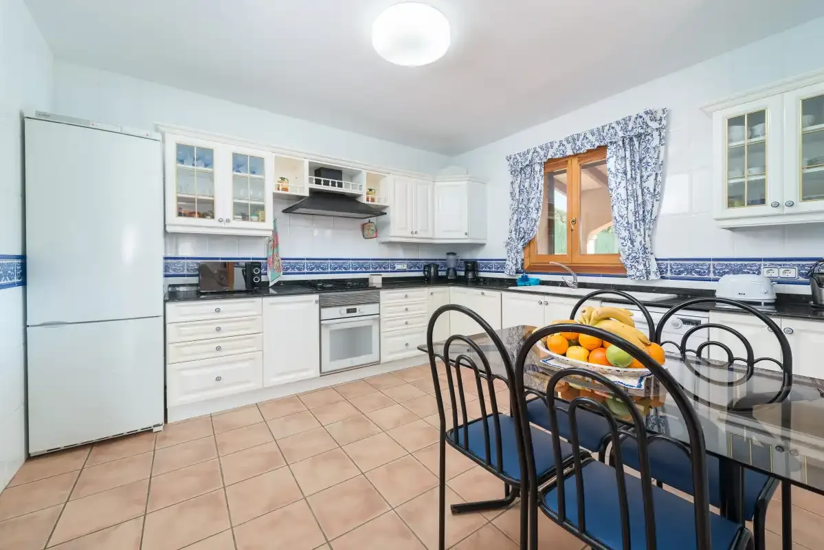 A bright kitchen with white cabinets and a dining table with chairs.