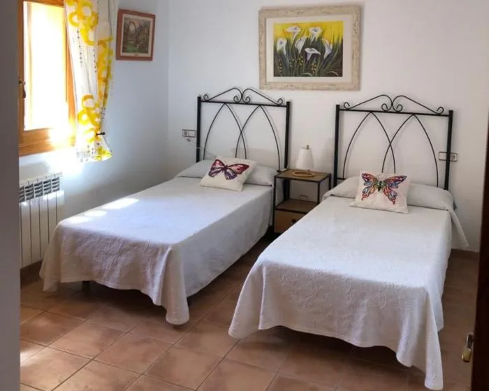 A bedroom with two single beds, a small bedside table, and framed artwork.