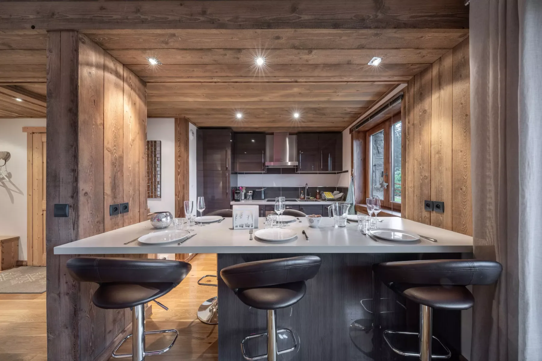 Un comedor con la mesa puesta da a una cocina abierta.
