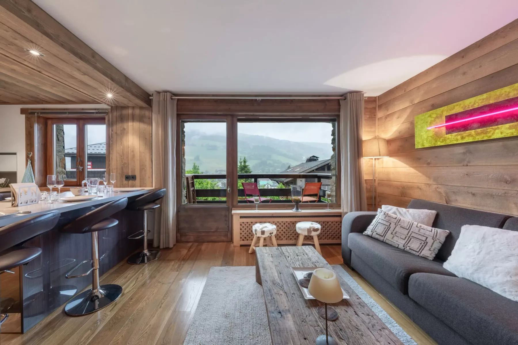 Living room with a dining counter and windows overlooking a green landscape.